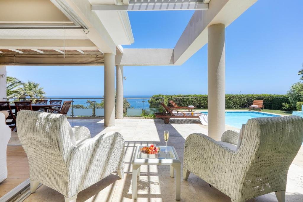 Covered patio with wicker chairs overlooking pool and ocean