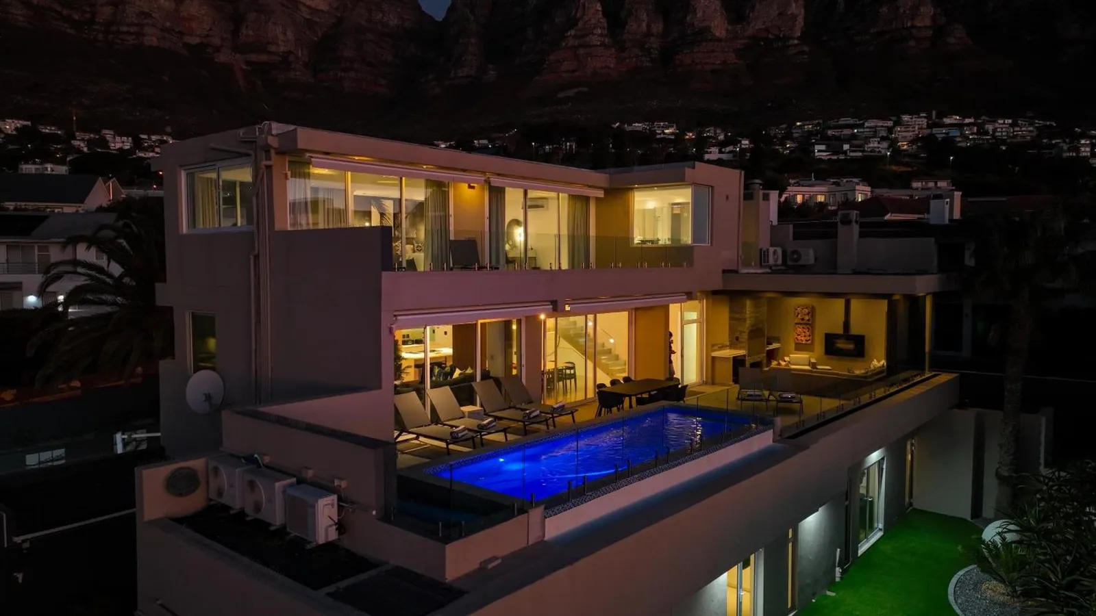The villa lit at night with the pool in the foreground