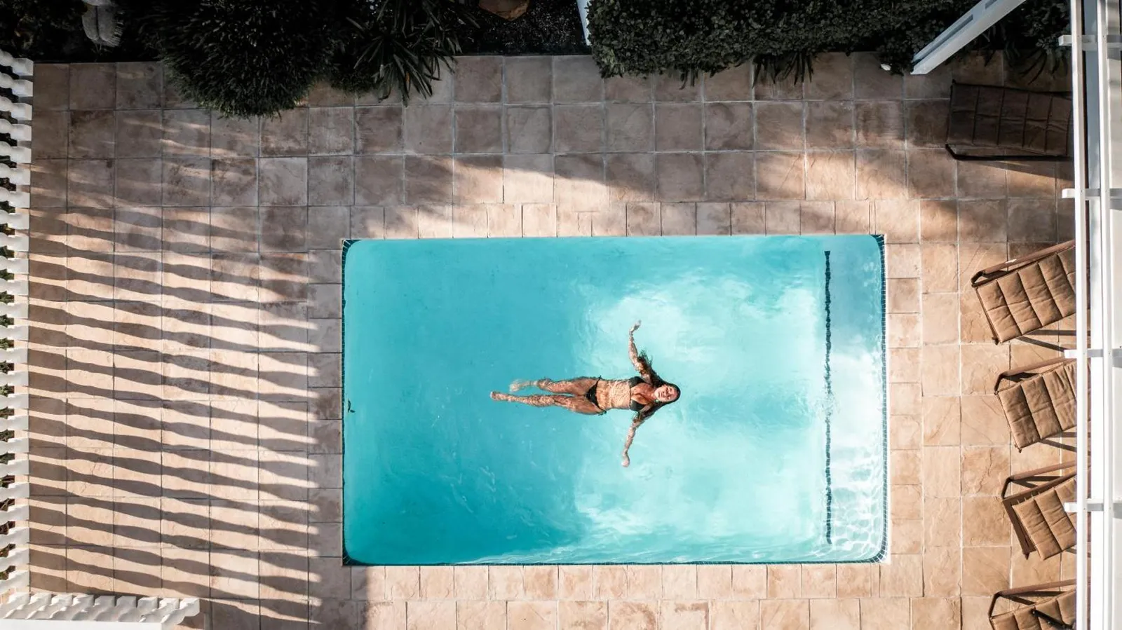 Swimmer in the pool on the sun-drenched terrace