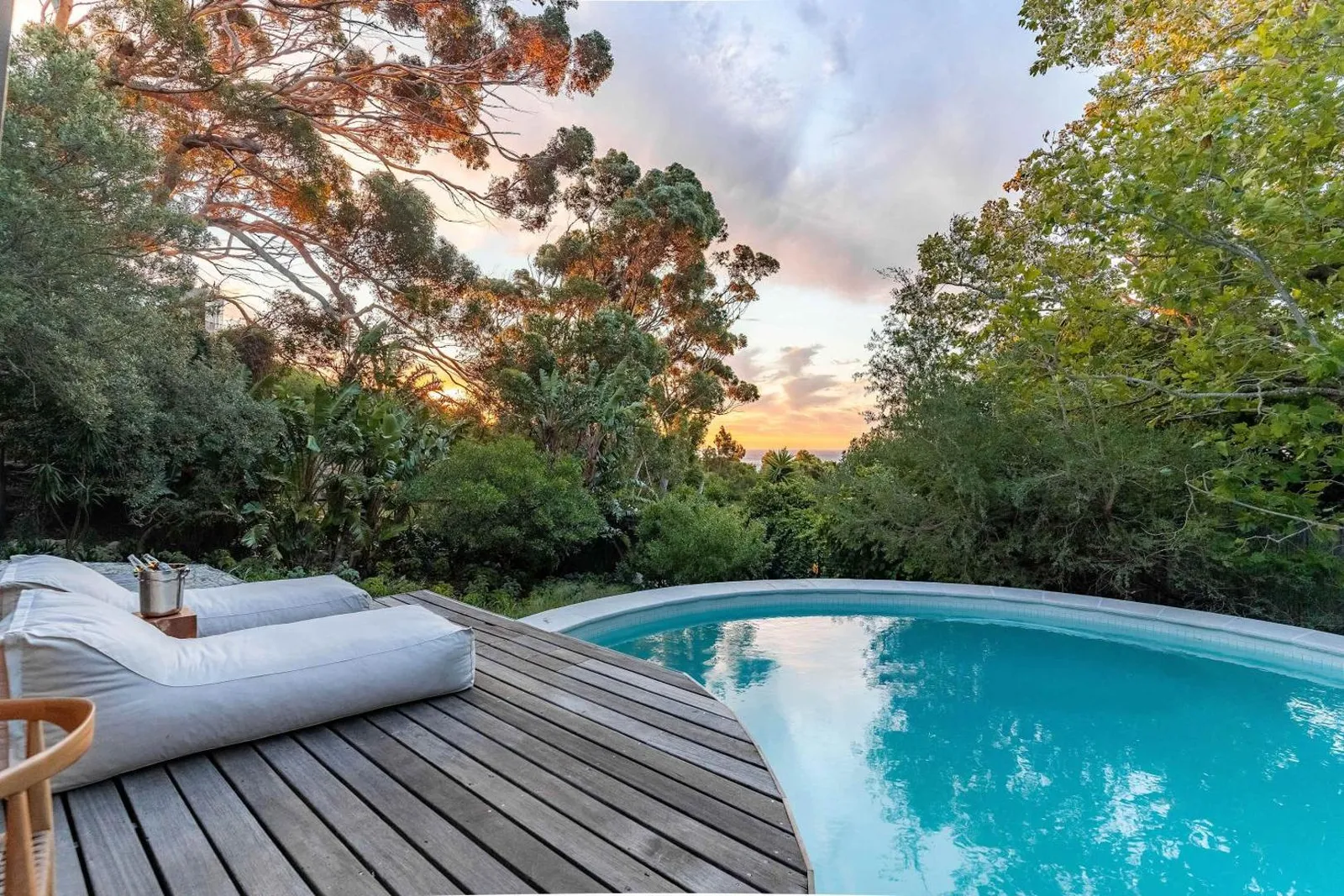 Pool deck with a daybed under the trees at sunset