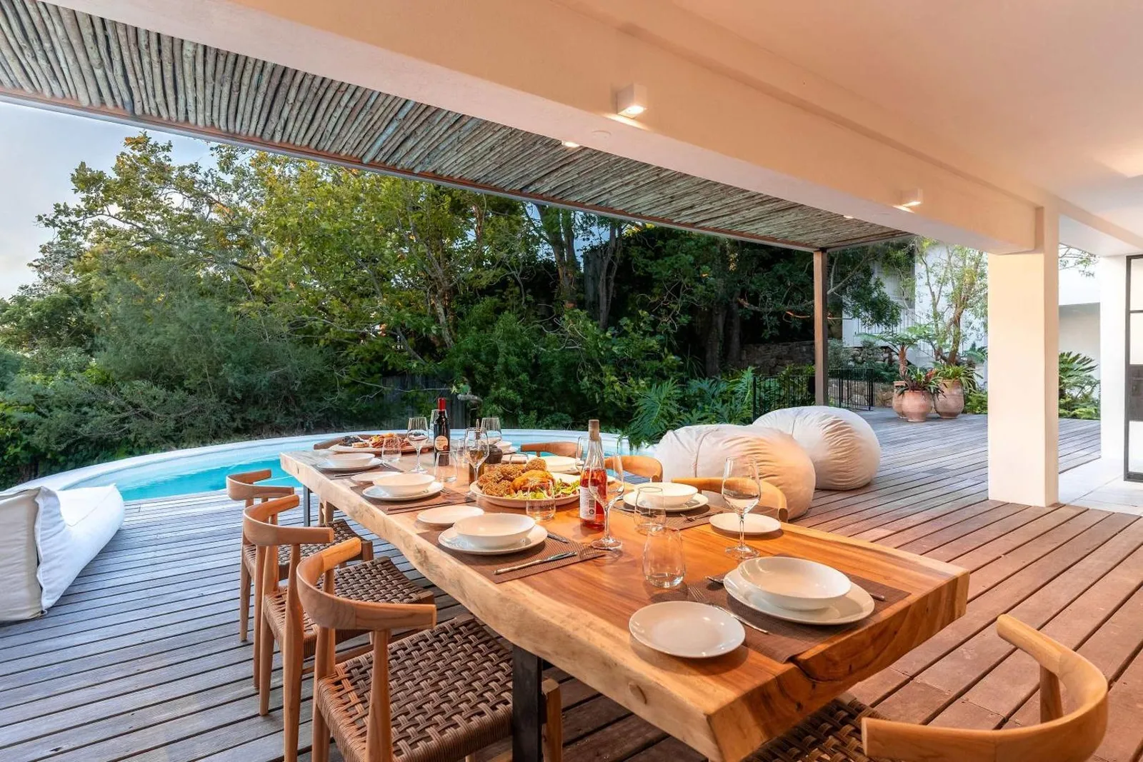Long outdoor dining table laid beside the pool