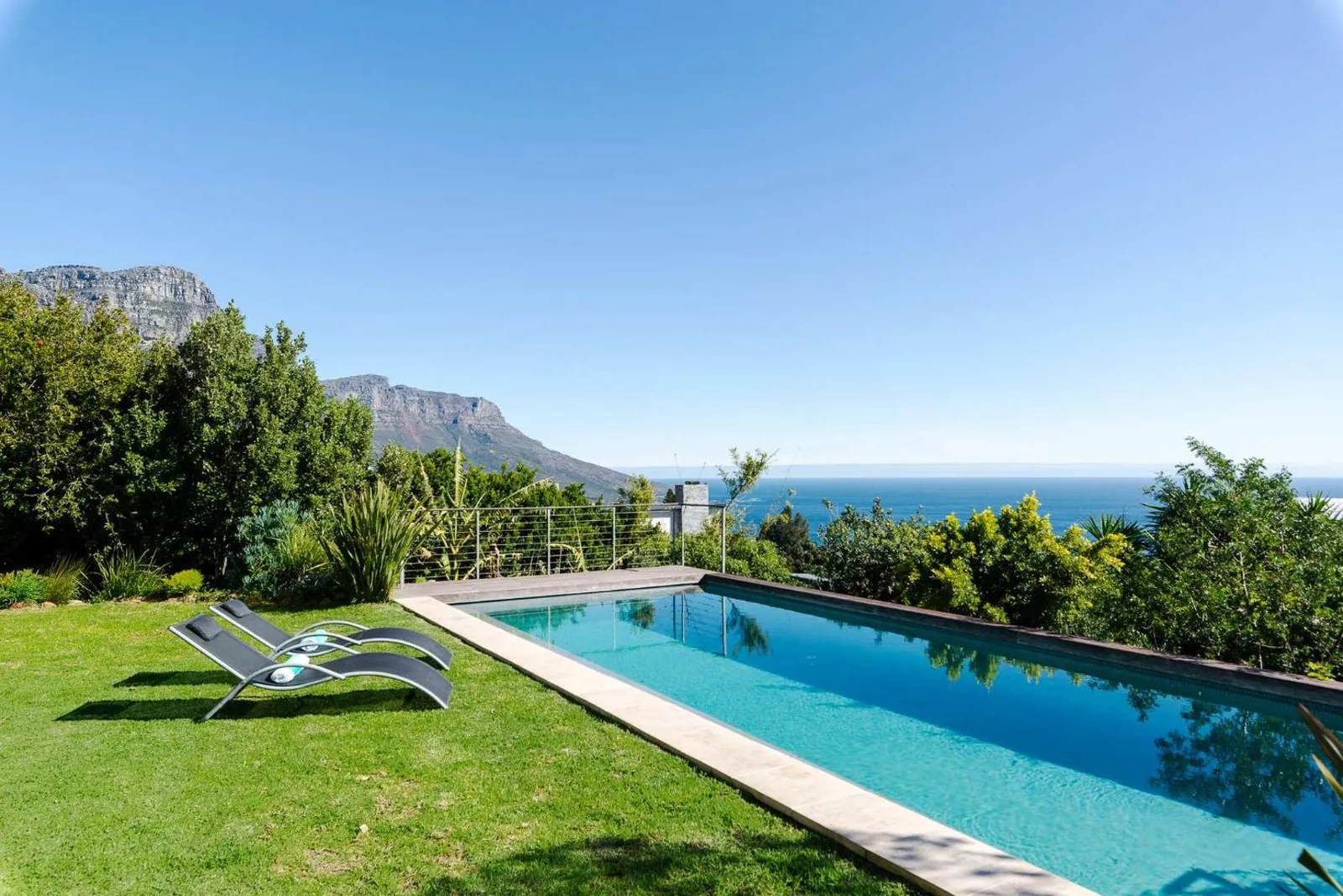 Pool and loungers on the lawn with the Twelve Apostles and ocean beyond