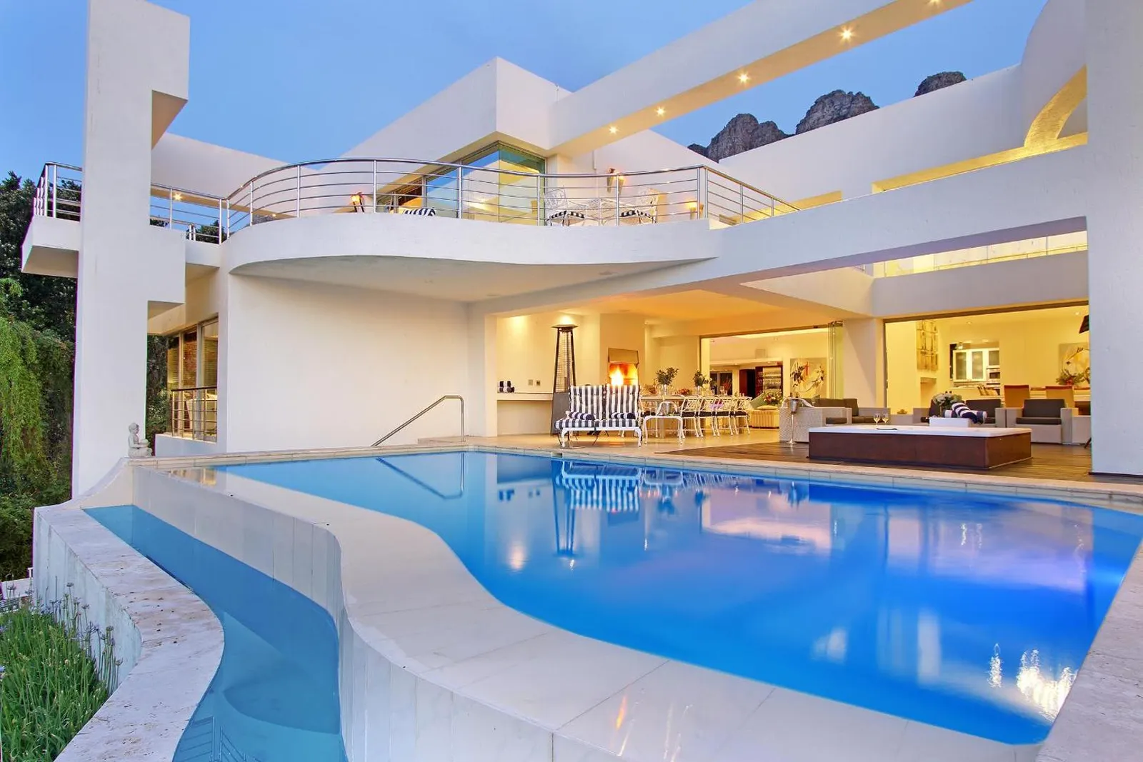 Pool lit at dusk with the open-plan interior glowing behind