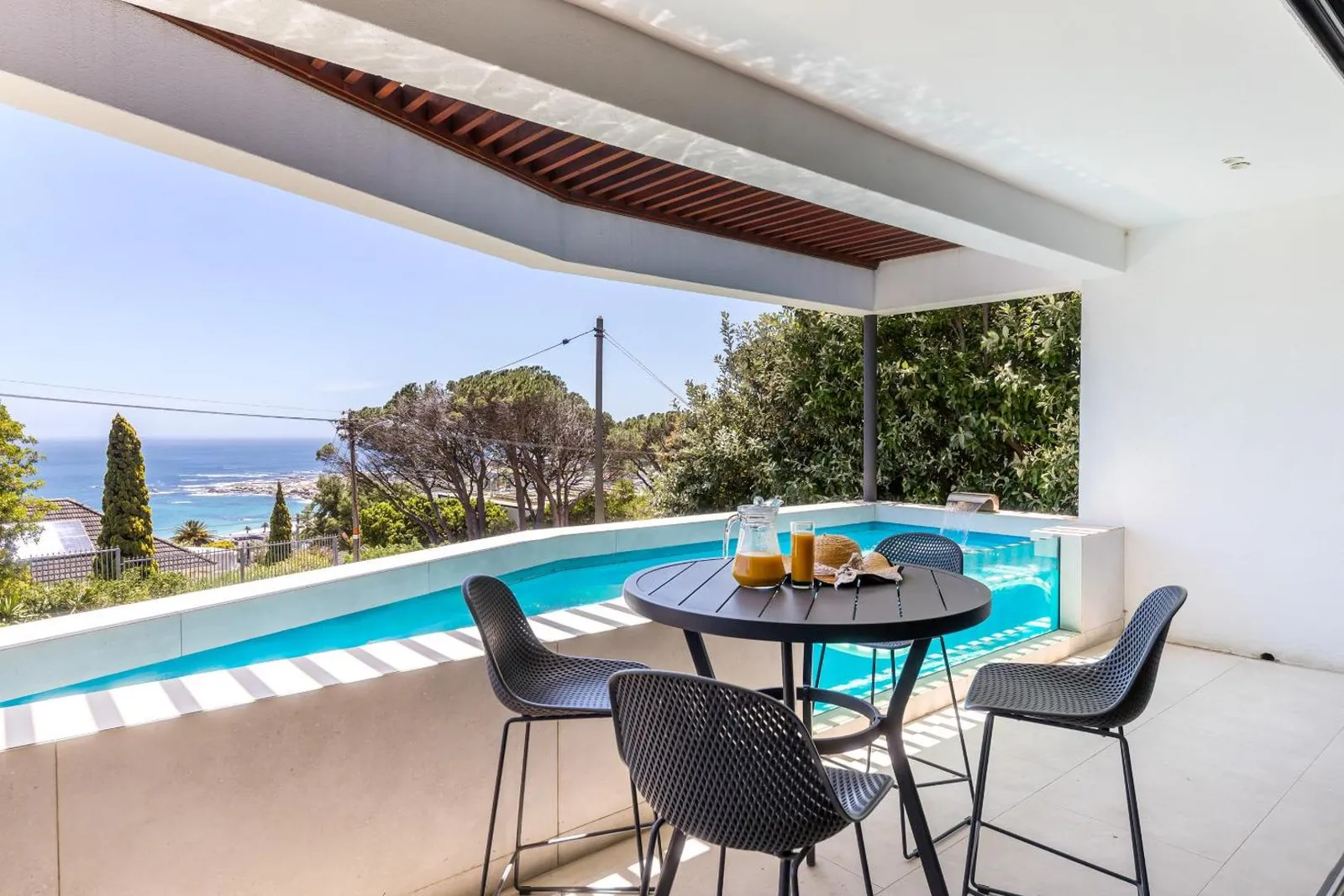 Covered terrace dining beside the heated pool with the sea beyond
