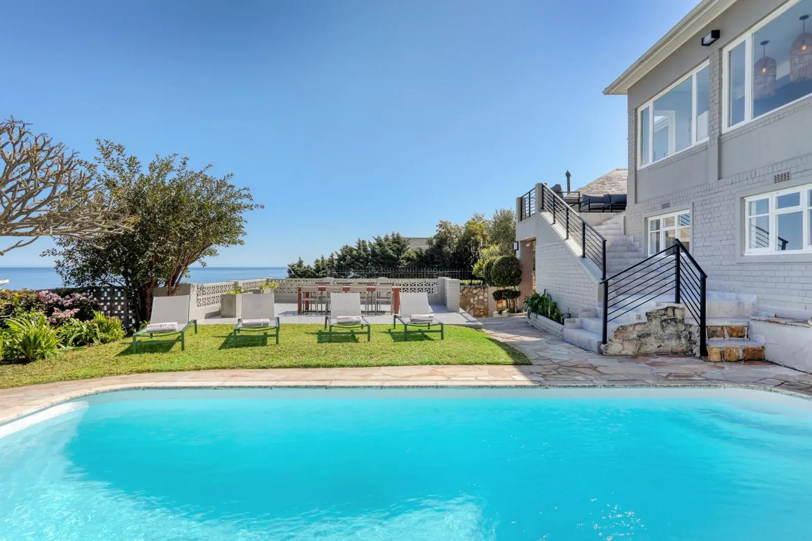 Pool and sun loungers on the lawn below the villa