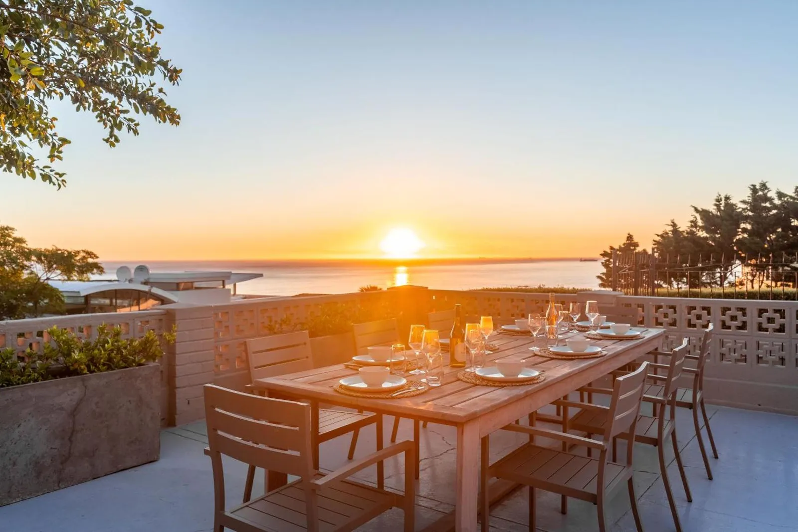 Terrace table laid for dinner as the sun sets over the sea