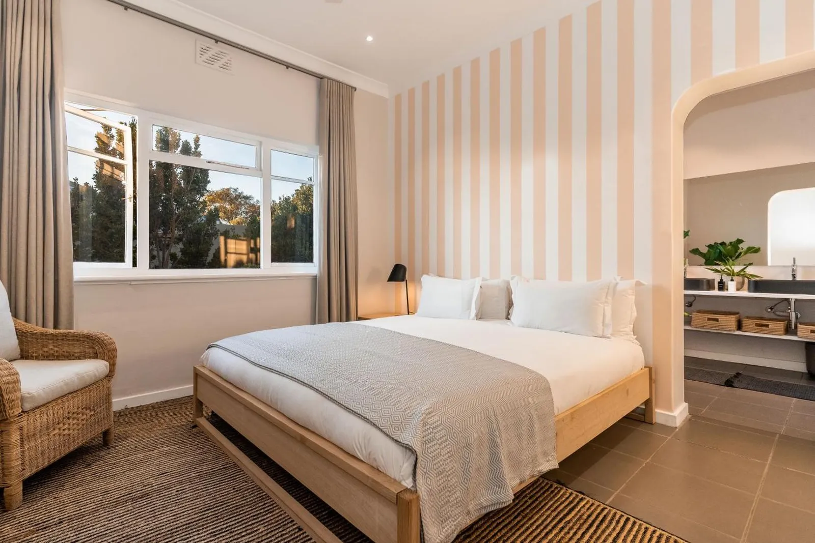 Bedroom with a striped feature wall and wicker armchair