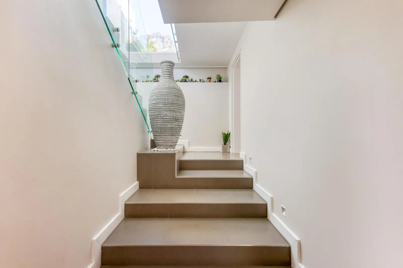 Sculptural staircase with a ceramic urn on the landing