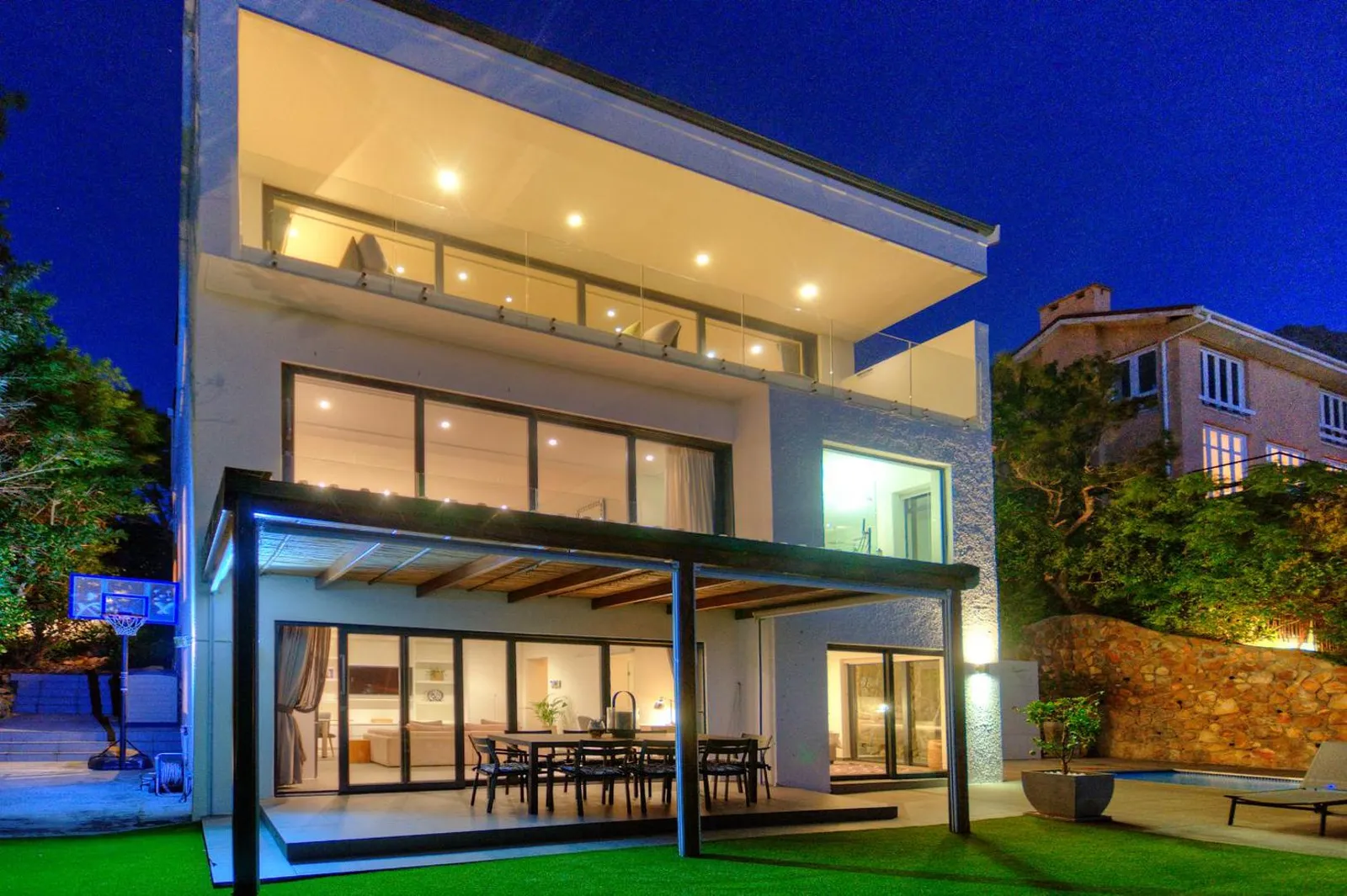 The villa lit at dusk with the pool in the foreground